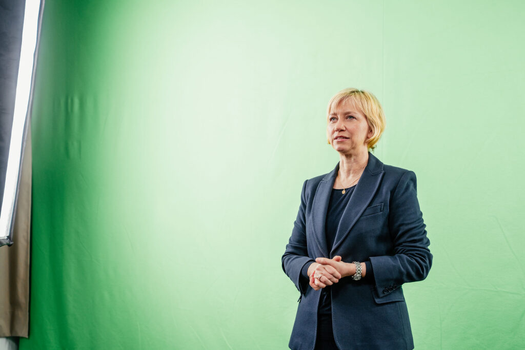 ECON VIS Mitarbeiterin vor dem Greenscreen im kleinen Studio