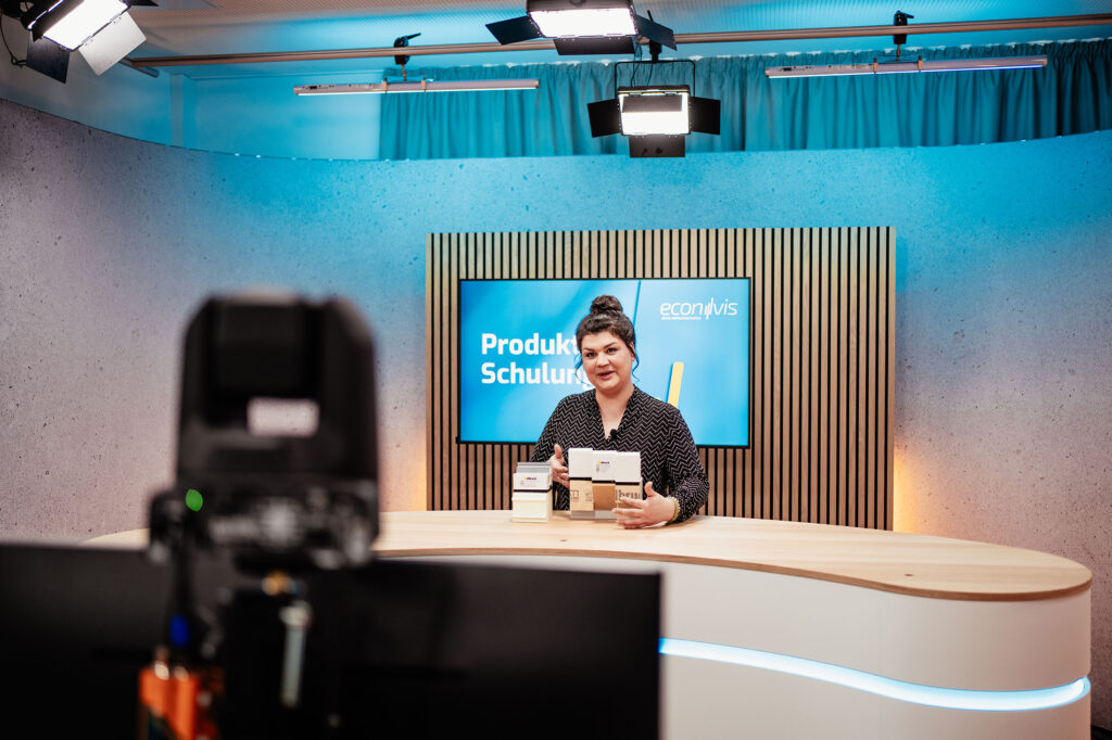 Frau während einer Produktpräsentation im großen Studio frontal vor der Kamera
